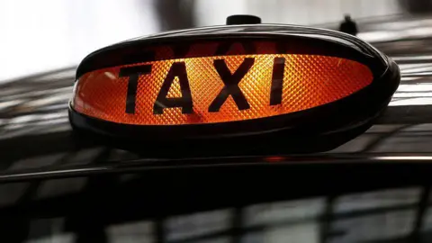 Getty Images An orange taxi light on top of a black cab.