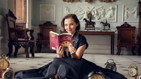 Netflix Mia McKenna-Bruce posing with an Agatha Christie novel