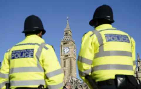 Part of the Palace of Westminster is seen between two Metropolitan Police officers in Parliament Square, London. 