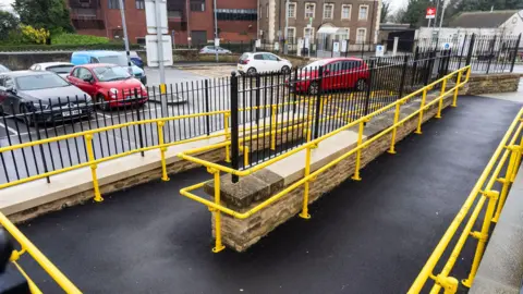 Wiltshire Council A path leading from a car park to a higher level with bright yellow handles 