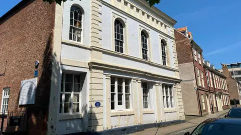 A large, off-white building on a residential street.