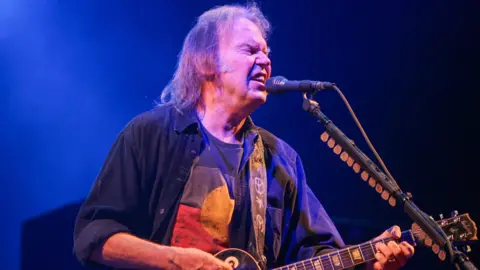 Getty Images Neil Young singing and playing his guitar on stage at the Glastonbury Festival in 2009