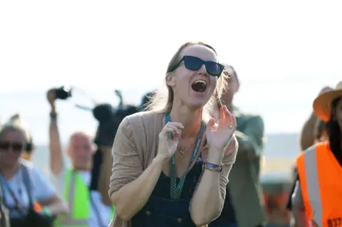 Emily Eavis shouts a greeting to festivalgoers as she opens the gates to Glastonbury