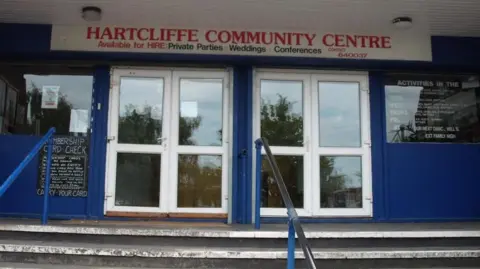 Hartcliffe Community Centre The entrance to Hartcliffe Community Centre. A white sign with red lettering hangs over two white, glazed double doors at the top of some steps. The walls to the centre are blue with other chalk board signage on them.