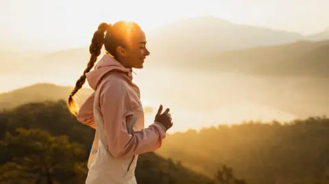A woman takes a run in the early morning sunlight