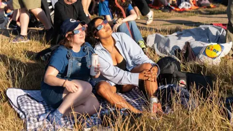 Denise Baker via Getty Images Women wear solar eclipse glasses to view the partial eclipse Parliament Hill, Hampstead Heath on August 12, 2026 in London, England. 