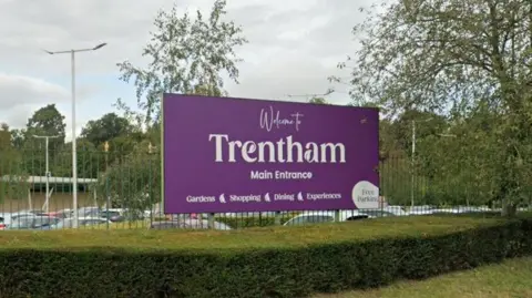 Google A purple entrance sign with white lettering that read 'Trentham'. There is a car park behind it.