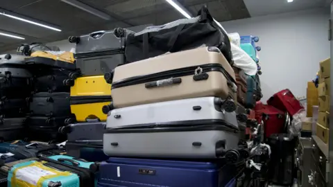 Thanyarat Doksone/BBC Piles of luggage are seen in a room