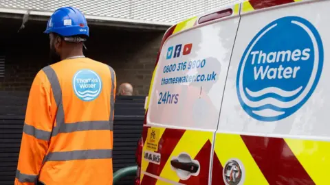 Getty Images Man in Thames Water hi-viz jacket standing next to a Thames Water van