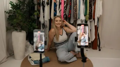 Amy Baldwin A woman in front of two smartphones. 