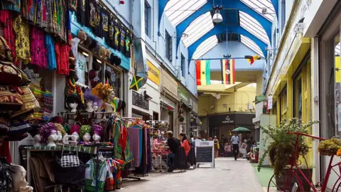 A general view of shops and eateries in Brixton Village, with clothes and accessories on display outside shops.