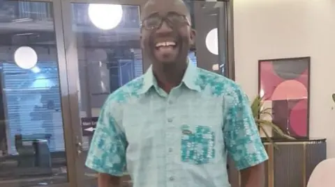 Akwasi Attua Akwasi is in a lilac short sleeved shirt in an office