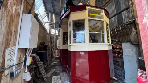 George Carden/BBC Tram 53 which has a red and cream coloured body with windows at the front and side. it also has an upper deck where people can sit