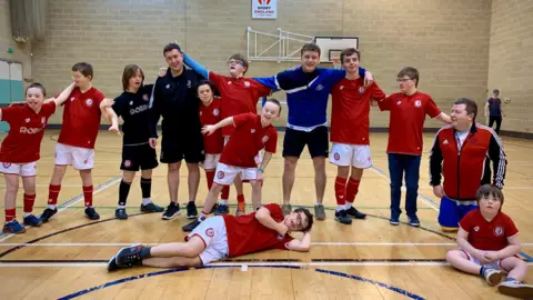 Bristol Down's Syndrome Football Club Bristol Down Syndrome Football Club players pose for a photo on an indoor pitch