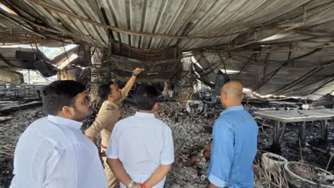 EPA Four men, including a police officer, stand amid the charred interiors of the nightclub, as they inspect the site of the fire incident