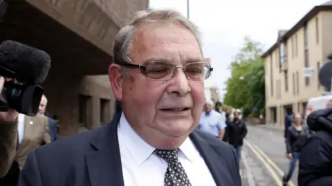 Lord Hanningfield in a navy suit leaving a court building