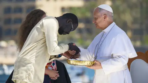 EPA El Papa León XIV recibe un regalo de un inmigrante senegalés durante una reunión con organizaciones que trabajan con inmigrantes en el puerto de Arguineguín, en Gran Canaria.