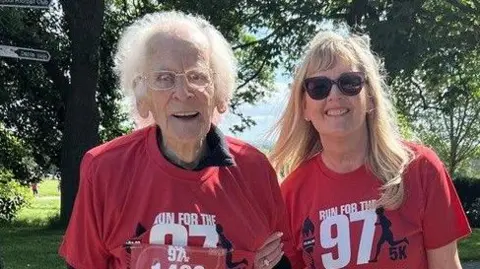 Erica Dillon Dennis Adelsberg and his daughter Gillian smile as they stand together for the picture. They're wearing red 97 tops.