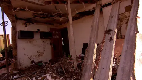 The house of the Matías family has been reduced to rubble, although some of the walls are still standing. There is litter on the floor and there is a door with the names of the boys still standing.