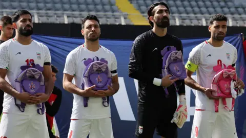 Iran's Hossein Kanaani, Shoja Khalilzadeh, Alireza Beiranvand and Mehdi Taremi hold school bags in memory of the victims of the girls school bombing in Minab, Iran 