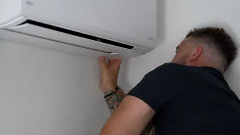An air conditioning unit being installed on a wall.