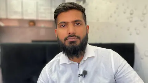 A man wearing a white shirt with a big beard