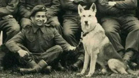 Emile Cortiel sitting cross-legged next to a dog