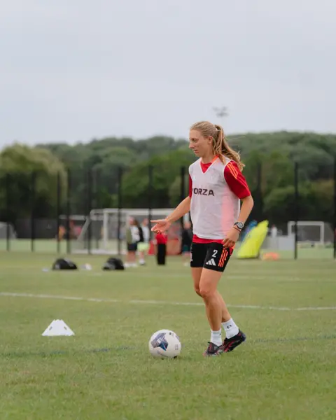 Exeter City Football Club Bow Jackson in football kit, with a white bib, about to kick a football