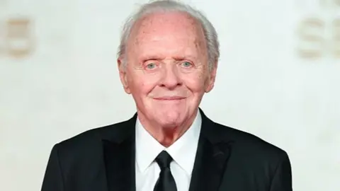 Sir Anthony Hopkins in a dark suit and tie with a white shirt
