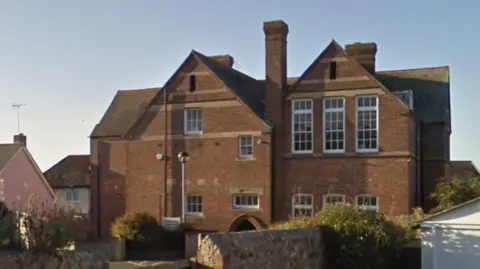 Google Google Street View of St Michael's Business Centre - a large two-storey red-brick building that resembles a Victorian School, with huge sash windows, a tall chimney and a large pitched roof.