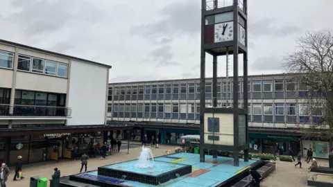 A view of Stevenage town centre showing the clock tower and water feature surrounded by shops