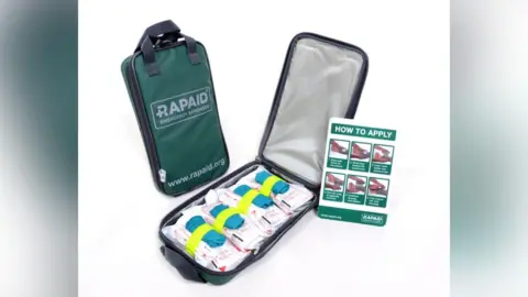 Rapaid The inside of a Rapaid kit showing four rolled bandages with blue surgical gloves attached