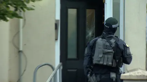 Armed police in front of a door