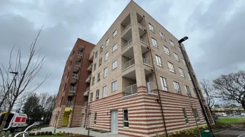Simon Dedman/BBC A modern block of flats of 5 storeys with some balconies. 