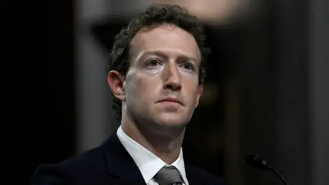 AFP via Getty Images Mark Zuckerberg, wearing a suit and grey tie, looks away from the camera with a grave expression as he is questioned by US lawmakers during a 2024 Senate hearing