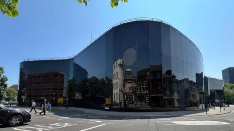 Stuart Howells/BBC The exterior of the Willis building in Ipswich. It is a completely glass building that has a curved shape around a road. Pedestrians can be seen walking past as well as cars driving past.