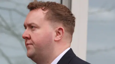 A man in a dark suit arriving at court