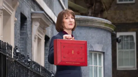 PA Media A woman with a brown bob haircut standing outside Downing Street holding a red briefcase.