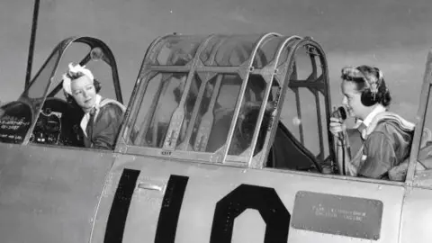 Getty Images View of WASP (Women's Airforce Service Pilot) Leila Mather (left), in the pilot's seat of her plane, listens as WASP Martha Jane Thomas speaks on a radio microphone, Sweetwater, Texas, May 1943.