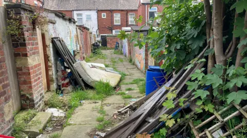 Rubbish is left in an alley behind people's house