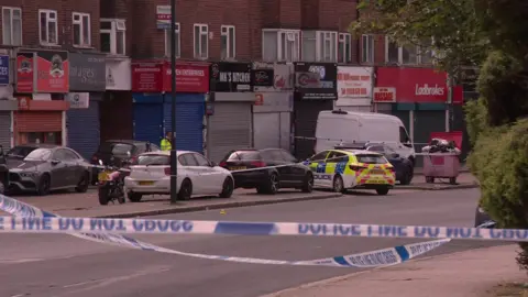 Police cars parked within a police cordon on Kingsbury Road