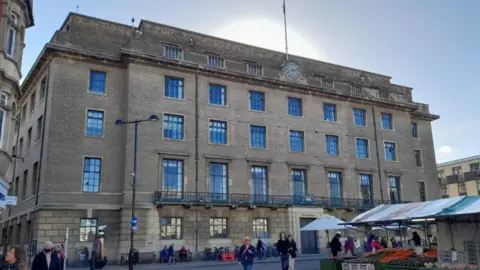 Local Democracy Reporting Service A view of the Cambridge City Council building from the outside. People can be seen walking around in the street.