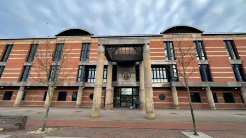 BBC A three-storey red brick court building with two stone columns either side of the front door.
