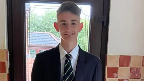 Katherine Williamson 15-year-old Andrew stands in his school uniform