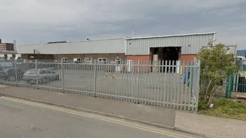 GOOGLE The current recycling centre warehouses clad in grey sheeting and surrounded by a high metal grey fence 

