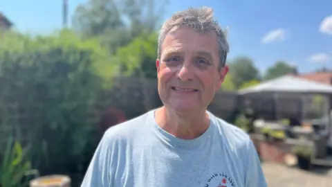 A man in grey t-shirt smiles 