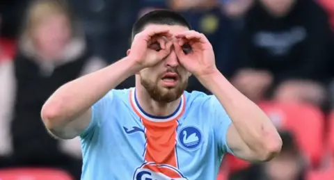 Zan Vipotnik with his hands over his eyes in a goggle-style goal celebration