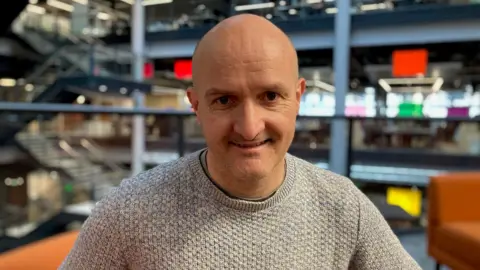 David Clubb, chair of the National Infrastructure Commission for Wales.  Sat in the BBC's Cardiff headquarters, looking at the camera wearing a light grey jumper.  