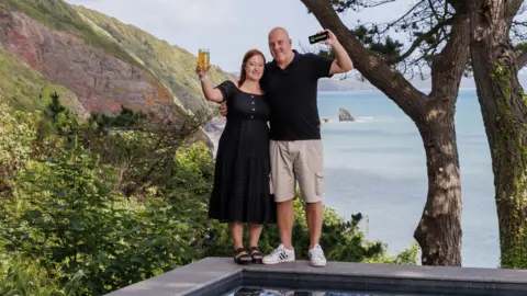 Omaze Darren Summers and wife Maria standing by the pool on their new beachside property in Cornwall