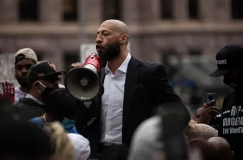 Getty Images White holds a megaphone in a crowd of people